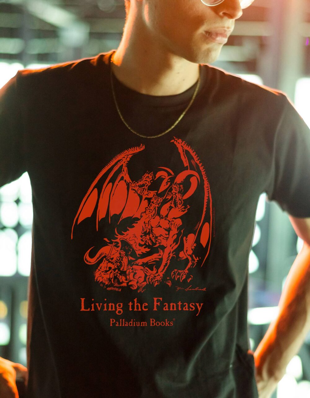 A black shirt with Living the Fantasy written in red on it and the palladium fantasy RPG first edition dragon above the text