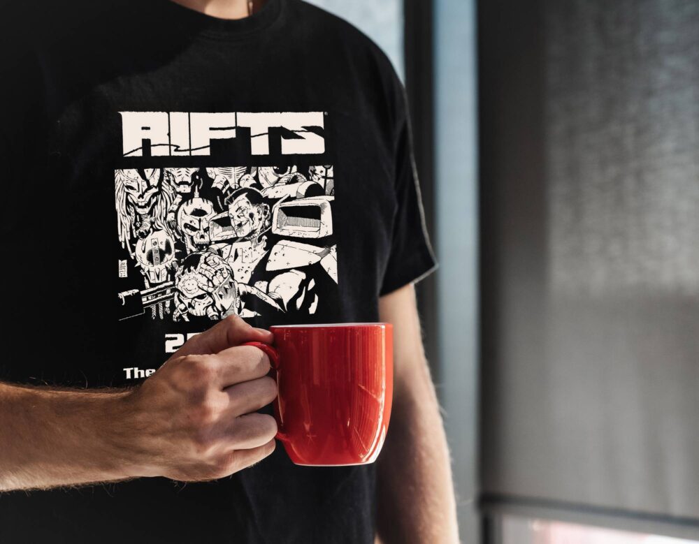 A black shirt with "Rifts 25 years the adventure continues" written in white on it and with a picture of a russian robot hunter smiling with borg heads on a wall behind him